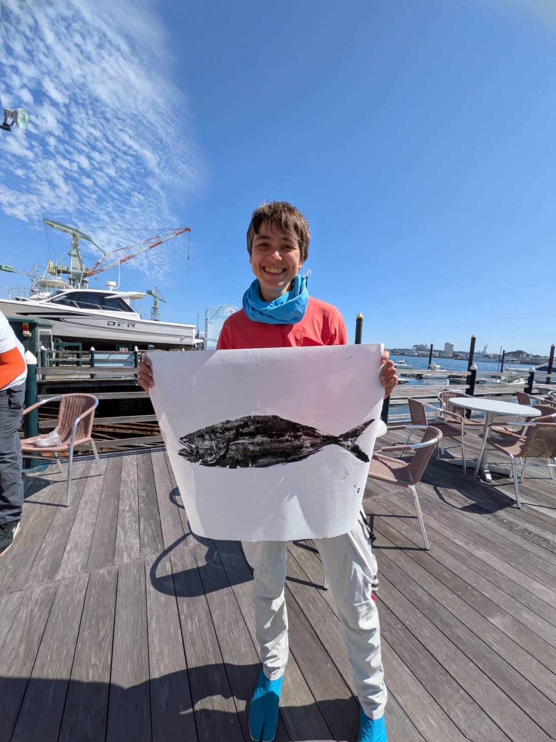 A guest holding a finished Gyotaku: a detailed black fish impression printed on white paper